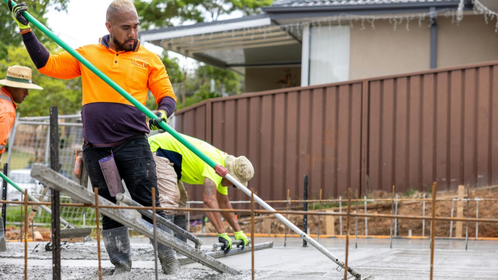 Concrete finishers screeding and bull-floating a freshly placed residential slab