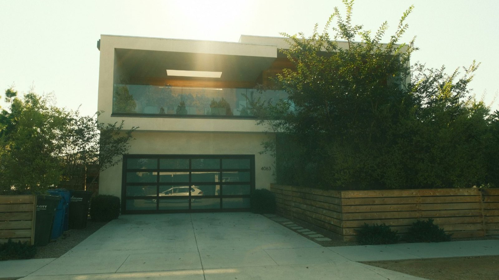 Concrete driveway and approach in front of a modern two-storey home at sunrise