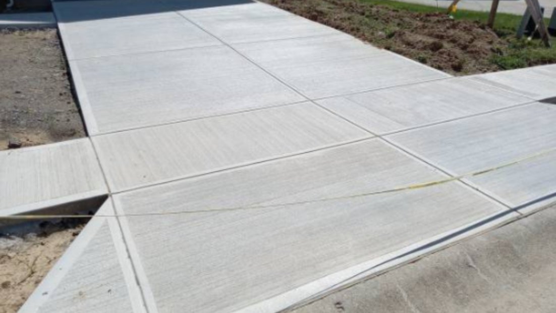 Newly poured concrete driveway with fresh saw-cut control joints at the garage apron