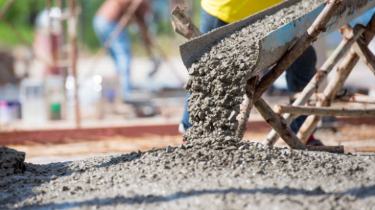 Wet concrete running down a mixer truck chute onto a prepared slab