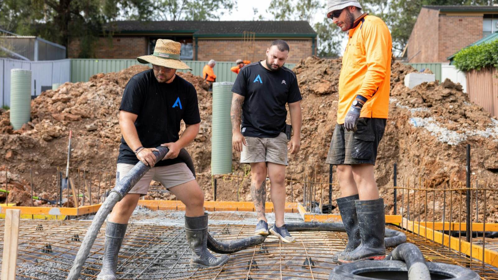 Concrete crew running a pump hose across a reinforced slab on chairs before placing